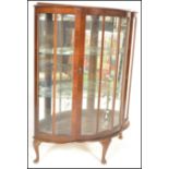 An early 20th Century walnut demi-lune china display cabinet with glazed panels, single door with