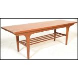 A mid century Danish influence teak wood long john coffee table being raised on tapering legs with a