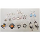 A collection of silver earrings including stud and drop earrings to include a pair of amber cabochon