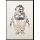 A stamped sterling silver pincushion in the form of a penguin set with glass eyes having a red