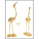 A pair of tall brass sculptural figures modelled as Cranes, stood upright with open bills set upon