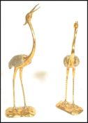 A pair of tall brass sculptural figures modelled as Cranes, stood upright with open bills set upon
