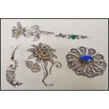 A collection of silver brooches to include a bar brooch set with a malachite panel, a rose brooch