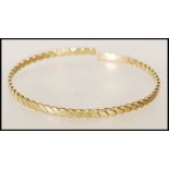 A 20th century stamped 9ct yellow gold bangle bracelet of twisted form, having an opening to the