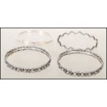 A group of four silver bangle bracelets to include a stamped 925 wave design bangle, a stamped 925