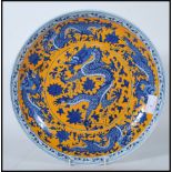 A 20th Century Chinese wall charger having hand painted on a yellow ground with five toed blue and