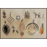 A selection of silver pendants to include two spiral design pendants, a marcasite and onyx panel