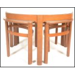 A retro 1970's Nathan teak and glass Trinity quartetto nest of table being raised on shaped legs