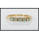 A hallmarked 9ct gold ring set with five round cut green stones. English hallmarks for Birmingham
