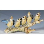 A 20th Century Italian ceramic bisque figurine group in the form of blue tit birds perched on a