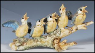 A 20th Century Italian ceramic bisque figurine group in the form of blue tit birds perched on a