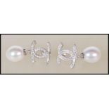 A pair of designer style silver and pearl drop ear