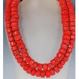 Two 20th Century beaded coral necklace, each having 47 large cylindrical beads set onto a black