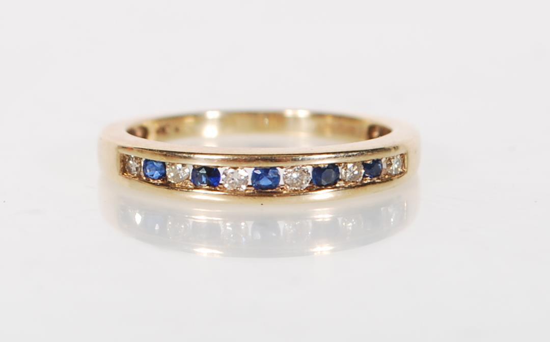 A stamped 9ct gold ring being channel set with alternate blue and white stones. Weight 2.3g. Size