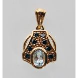 A stamped 9ct yellow gold pendant set with a oval cut blue stone flanl by blue accent stone. Gross