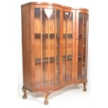 A 20th Century Art Deco walnut display cabinet of kidney form raised on ball and claw feet and