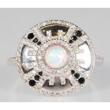 An impressive silver ring of round form set with a central opal having CZ's and black stones around.