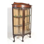 A 1920's Queen Anne mahogany bow front / demi lune leaded glass display cabinet being raised on claw