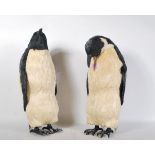 A pair of contemporary life size penguin figurines having a textured dried grass construction.