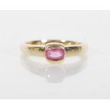 An English hallmarked 9ct gold ring set with a single oval cut pink stone. Hallmarked Birmingham
