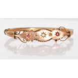 A late 19th Century Victorian 9ct gold bangle bracelet having two gypsy set red stones, with