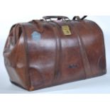 A vintage mid 20th Century brown leather gladstone bag having the leather strap closures to the