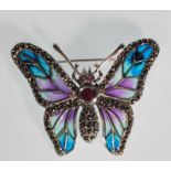 A silver and plique a jour brooch in the form of a butterfly having a central red stone and eyes