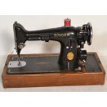 A vintage mid 20th Century electric Singer sewing machine set on a wooden base within a faux