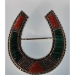 A sterling silver brooch in the form of a horseshoe set with coral and malachite panels. Stamped