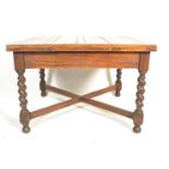 An early 20th Century oak drawer leaf dining table raised on barley twist supports united by 'X'