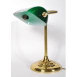 A vintage 20th Century bankers desk lamp having an adjustable green glass shade raised on a brass