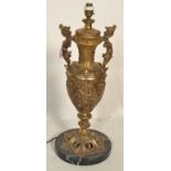 A large 20th Century twin handled gilt metal table lamp of urn shape form having pictorial relief