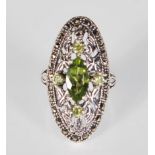 A silver and marcasite Art Nouveau style ladies dress ring of oval form set with a central peridot