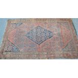 An early 20th century Persian / Islamic rug having central blue ground medallion on large red ground