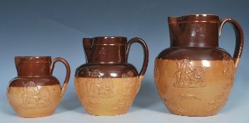 A group of three Doulton Lambeth salt glazed graduating harvest jugs, Applied relief decorations