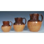 A group of three Doulton Lambeth salt glazed graduating harvest jugs, Applied relief decorations