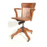 An early 20th century golden oak Industrial office swivel chair / desk armchair being raised on