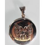 A silver picture locket of round form having applied filigree butterfly to the front set with rubies