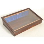 A 20th Century antique style wooden shop counter top display case having a sloped glazed lid with