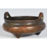 A cast bronze Chinese censer bowl of small proportions being open topped, raised on three feet