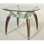 A contemporary two tier sputnik style glass top side table raised on metal and faux wood splayed leg