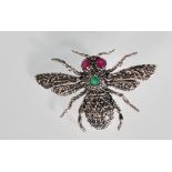 A large silver brooch in the form of a bug set with ruby eyes and a green stone. Heavily decorated