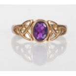 A hallmarked 9ct gold ring having an oval cut purple stone with celtic design pierced decoration