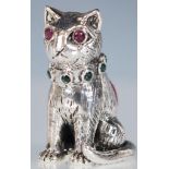 A silver pincushion in the form of a cat having an emerald collar and ruby eyes with red velvet