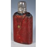 An early 20th Century glass hip flask having a red leatherette casing with white metal screw measure