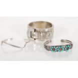 A group of three silver bangle bracelets to include a silver hallmarked hinged bangle with raised
