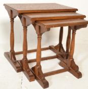 A 20th Century antique style oak nest of three tables raised on turned supports terminating in