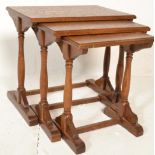 A 20th Century antique style oak nest of three tables raised on turned supports terminating in