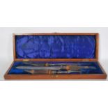 A late 19th Century Victorian oak cased carving set having stag horn handles with silver