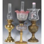 A group of three oil lamps dating from the early 20th Century one of simple brass form with